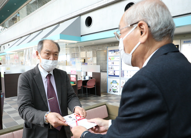 水野社長から町長に寄付目録を手渡し